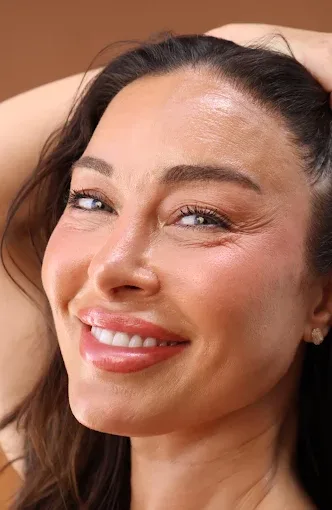 A smiling woman with her hand in her hair