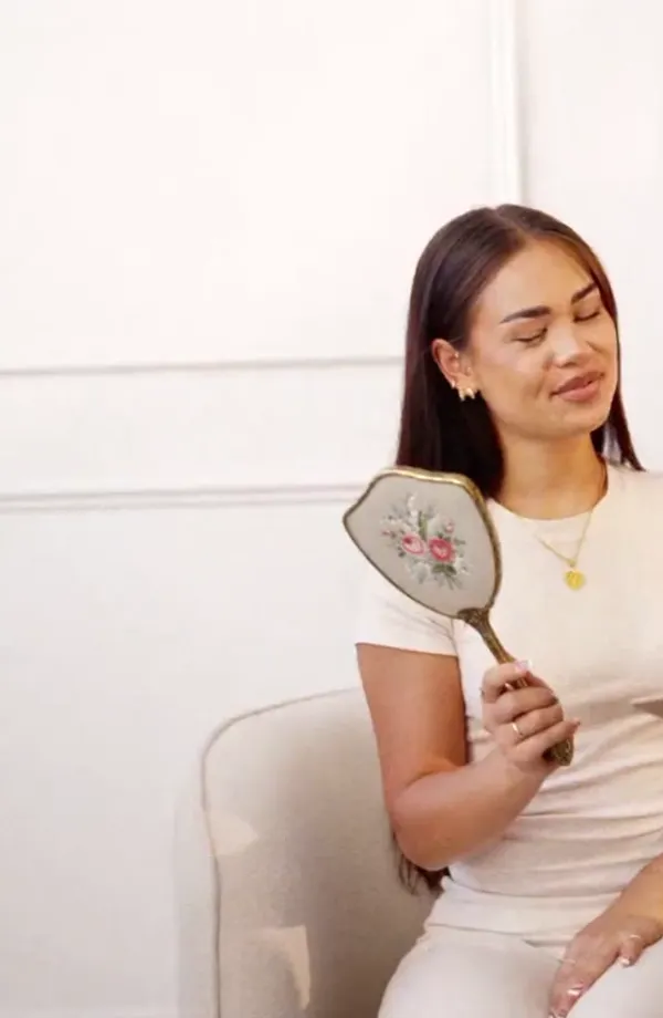 A client looking into a hand mirror during her consultation