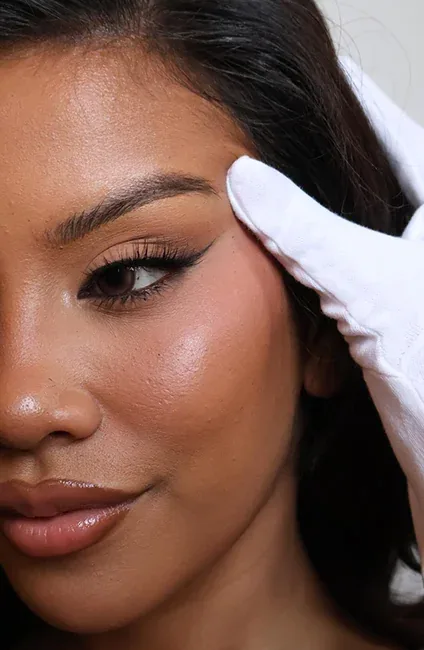 A gloved hand at a woman’s brow