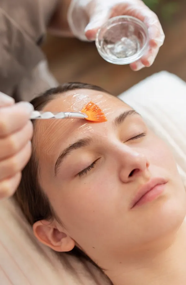A peel being brushed onto a client’s forehead