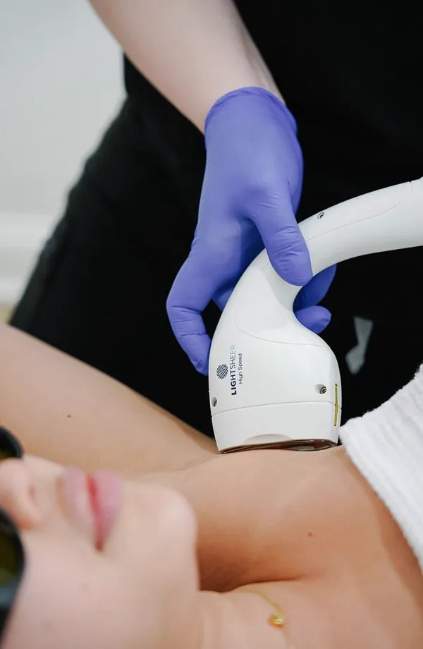 A gloved hand holding a laser hair removal handpiece